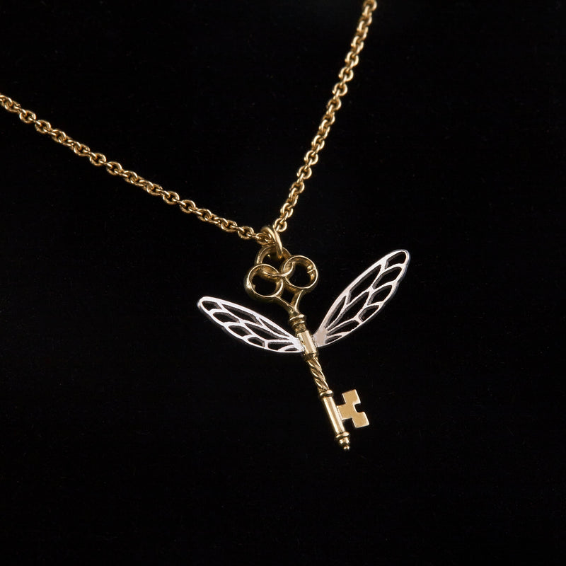 Officially licensed Harry Potter Winged Key pendant in solid 14k yellow gold with silver wings on a black background. Also available in sterling silver, 18k yellow gold, and platinum. 
