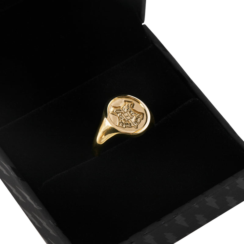 Close view of officially licensed Harry Potter Hogwarts Crest Signet Ring in solid 14k yellow gold resting in a black ring box on a white background. Also available in sterling silver, 14k white gold, 18k yellow gold, and platinum.
