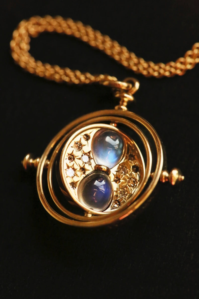 Officially licensed Harry Potter spinning Time Turner necklace in 14k yellow gold set with natural moonstones and diamonds on a black background. Also available in 14k white, 18k rose, 18k yellow gold, and platinum. 
