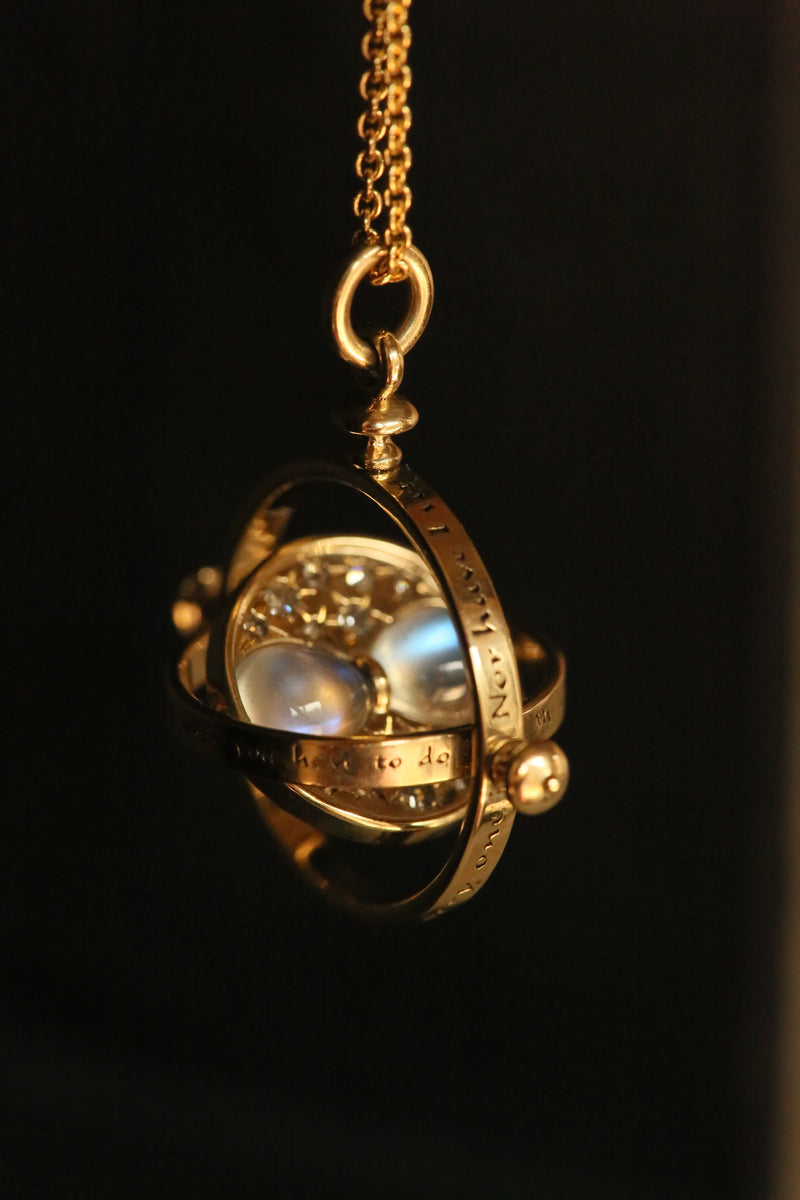 Officially licensed Harry Potter spinning Time Turner necklace in 14k yellow gold set with natural moonstones and diamonds on a black background. Also available in 14k white, 18k rose, 18k yellow gold, and platinum. 