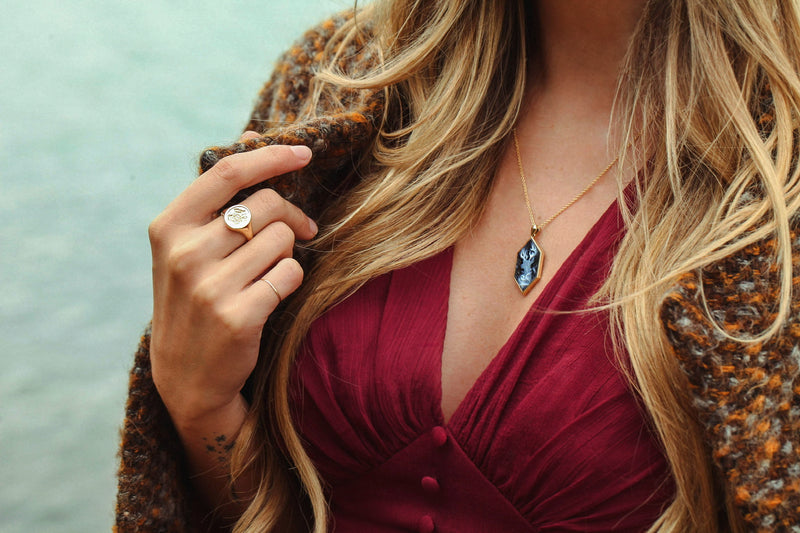 Model wearing an officially licensed Harry Potter Hogwarts Crest Signet Ring and Patronus Cameo Necklace in 14k yellow gold. Also available in other precious metals. 