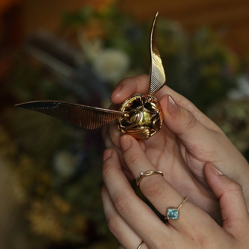 Model holding officially licensed Harry Potter Golden Snitch ring box in 14k yellow gold. Also available in gold plated sterling silver and platinum. 