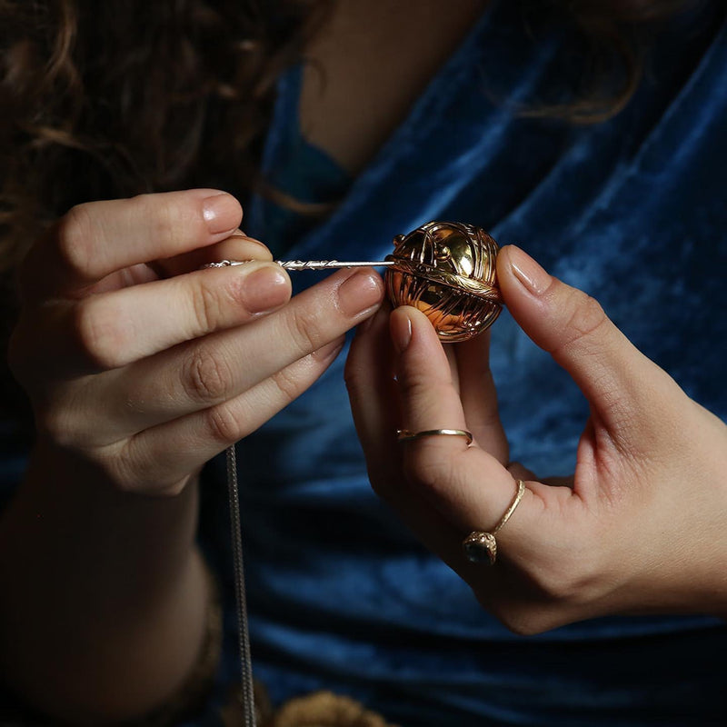 Model holding officially licensed Harry Potter Golden Snitch ring box in 14k yellow gold using Hermione’s wand in sterling silver to open the secret catch. Also available in gold plated sterling silver and platinum. 